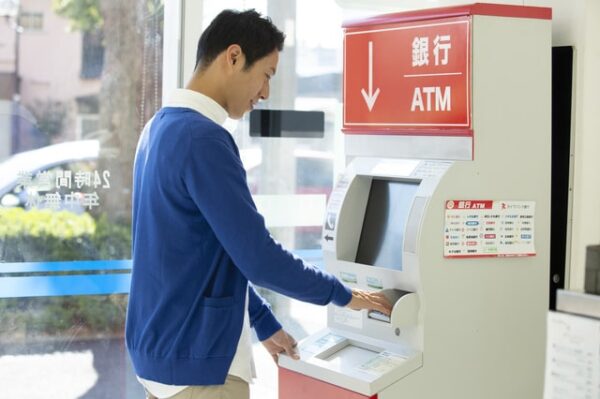 クレジットカードでコンビニ銀行ATMからキャッシングする男性